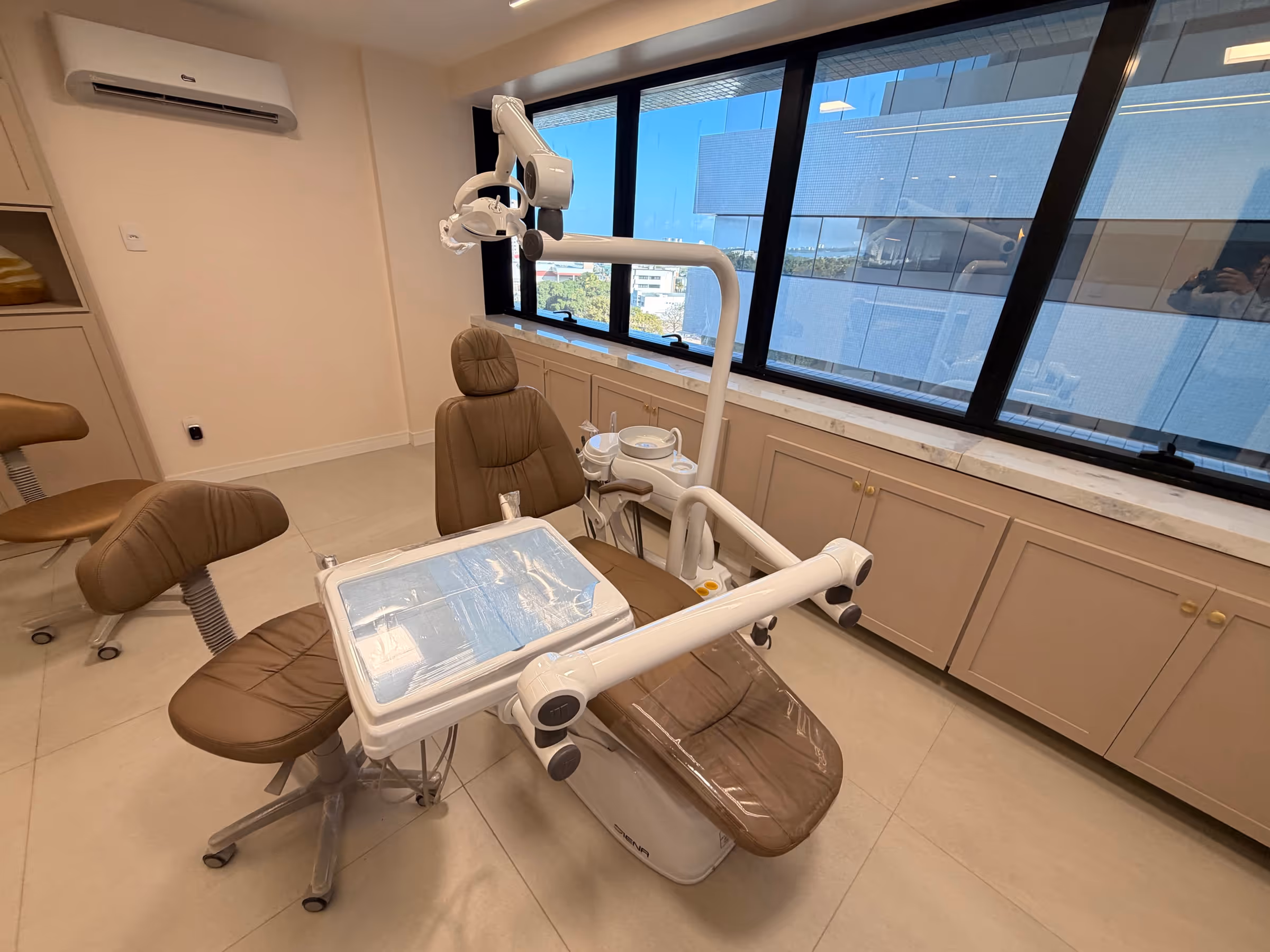 Cadeira odontológica junto à janela, com vista da cidade de Aracaju